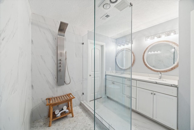 bathroom with vanity, a textured ceiling, and tiled shower