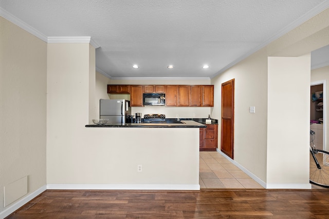 kitchen with kitchen peninsula, light wood-type flooring, crown molding, and black appliances