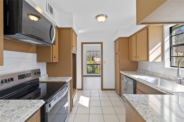 kitchen featuring sink, light stone counters, backsplash, light tile patterned floors, and appliances with stainless steel finishes