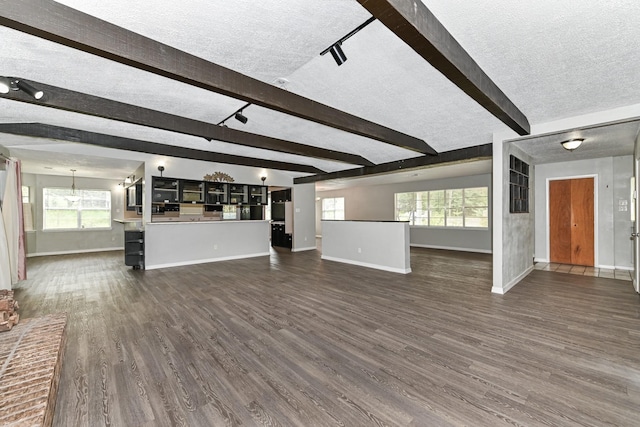 unfurnished living room featuring beam ceiling, dark wood-type flooring, and a textured ceiling