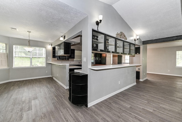 kitchen featuring kitchen peninsula, decorative light fixtures, vaulted ceiling, and dark hardwood / wood-style floors