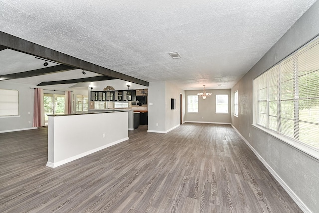 unfurnished living room with beamed ceiling, a notable chandelier, dark hardwood / wood-style flooring, and a textured ceiling