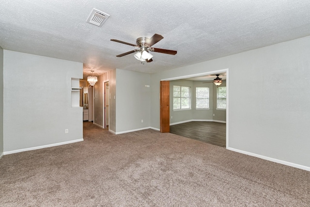 spare room featuring carpet, ceiling fan with notable chandelier, and a textured ceiling