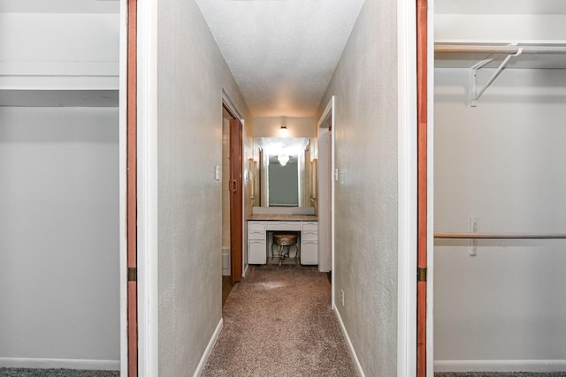 hall with a textured ceiling and carpet floors