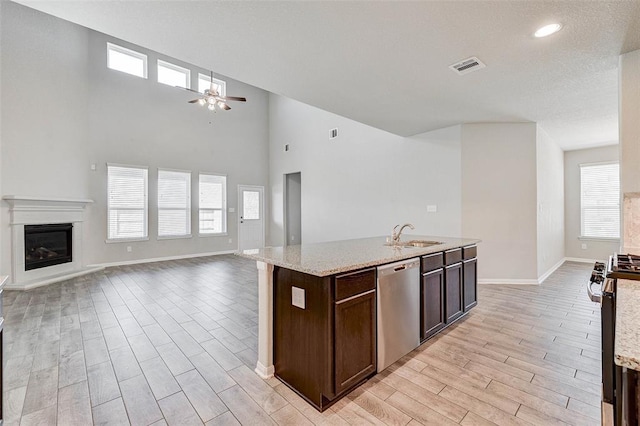 kitchen with a center island with sink, sink, ceiling fan, dark brown cabinetry, and stainless steel appliances