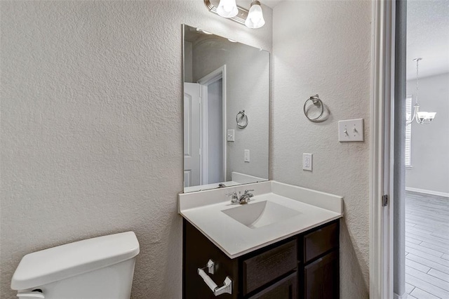 bathroom with vanity, toilet, and an inviting chandelier