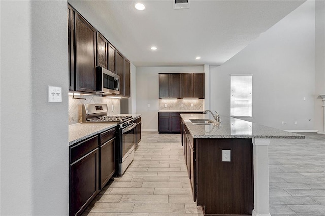 kitchen featuring sink, a center island with sink, dark brown cabinets, and appliances with stainless steel finishes