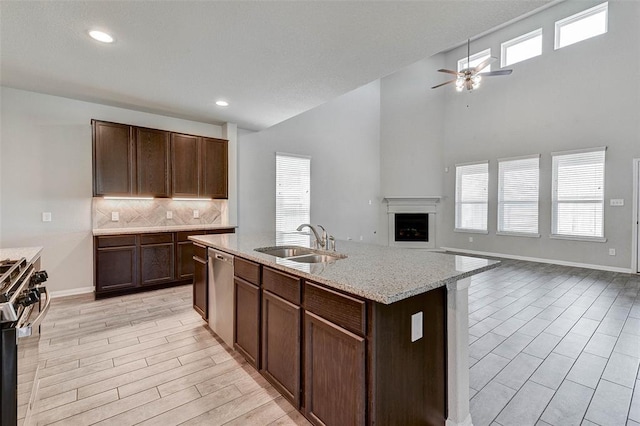 kitchen featuring ceiling fan, sink, tasteful backsplash, an island with sink, and appliances with stainless steel finishes