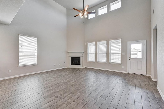 unfurnished living room featuring a high ceiling and ceiling fan