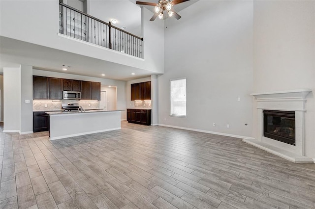 unfurnished living room with ceiling fan and a high ceiling