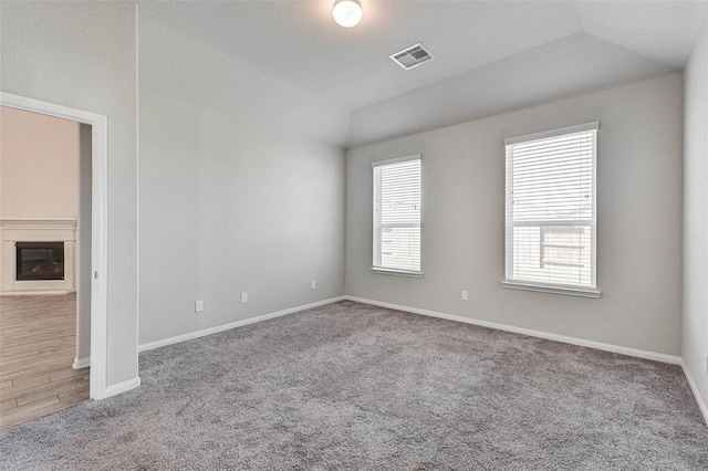 carpeted spare room with vaulted ceiling