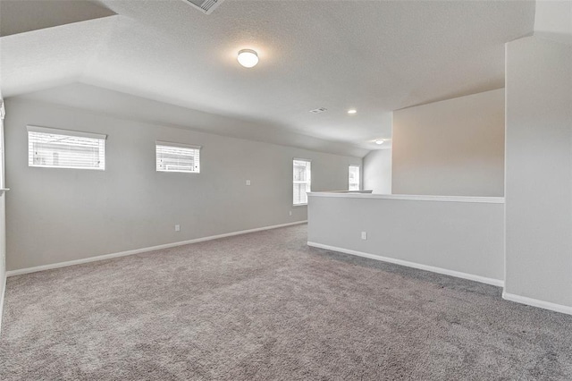 empty room featuring carpet flooring, a textured ceiling, and vaulted ceiling