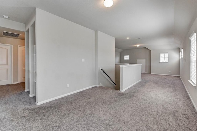 spare room featuring light colored carpet and vaulted ceiling