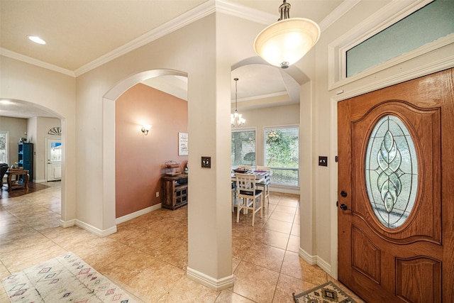 tiled foyer entrance featuring ornamental molding and a notable chandelier