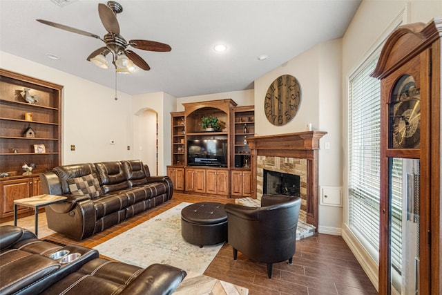 living room with plenty of natural light, ceiling fan, a fireplace, and built in shelves