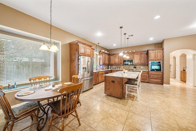 kitchen featuring a center island, stainless steel appliances, an inviting chandelier, pendant lighting, and decorative backsplash