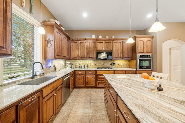 kitchen with backsplash, light stone counters, stainless steel appliances, sink, and decorative light fixtures