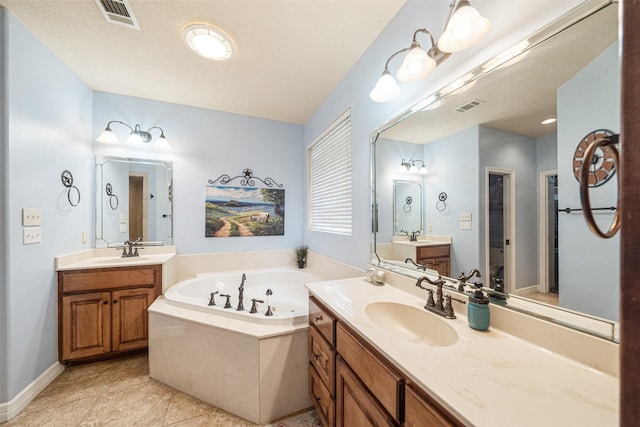 bathroom with tile patterned flooring, vanity, and tiled bath