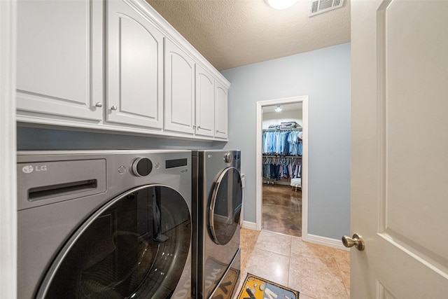 washroom featuring cabinets, light tile patterned floors, a textured ceiling, and washing machine and clothes dryer