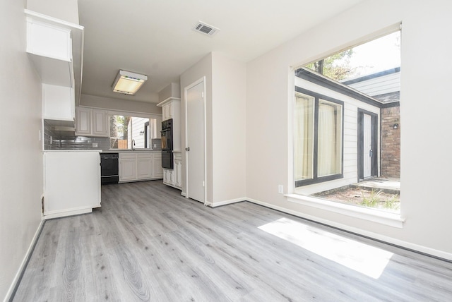 kitchen with sink, light wood-type flooring, white cabinetry, and black appliances