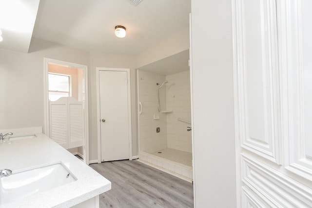 bathroom featuring tiled shower, wood-type flooring, and vanity