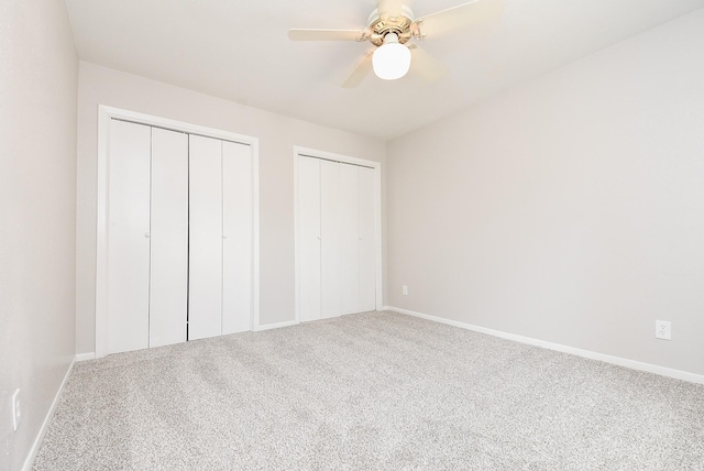 unfurnished bedroom featuring carpet flooring, multiple closets, and ceiling fan