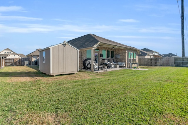 rear view of property featuring a lawn, a patio, and a shed