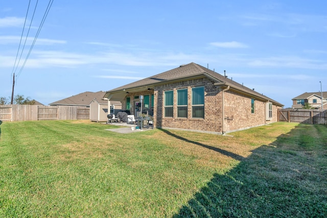 rear view of house featuring a yard, a patio, and a shed