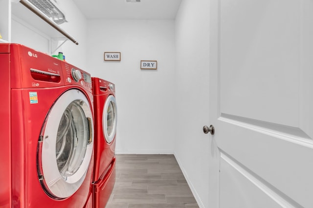 washroom with light hardwood / wood-style floors and washing machine and clothes dryer