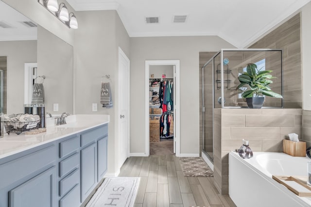 bathroom featuring vanity, ornamental molding, independent shower and bath, and vaulted ceiling