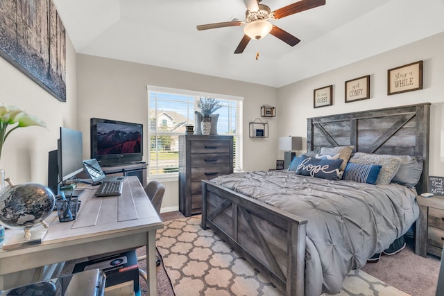 carpeted bedroom featuring a tray ceiling and ceiling fan