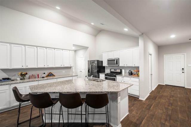 kitchen featuring light stone countertops, a breakfast bar, stainless steel appliances, a kitchen island with sink, and white cabinetry