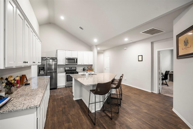 kitchen with appliances with stainless steel finishes, white cabinetry, a kitchen island with sink, and light stone counters