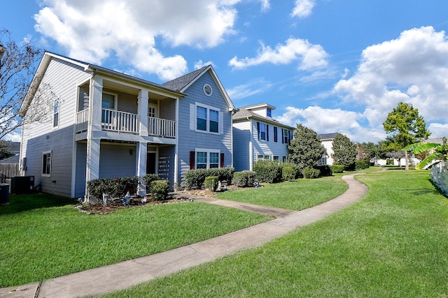 exterior space with cooling unit, a balcony, and a front yard