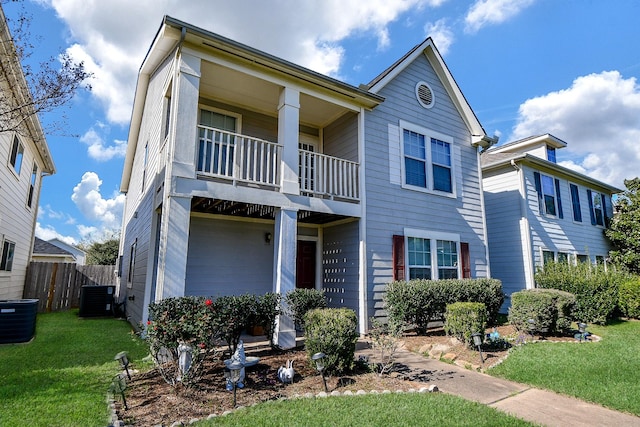 townhome / multi-family property with cooling unit, a balcony, and a front lawn