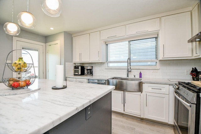 kitchen with appliances with stainless steel finishes, white cabinetry, hanging light fixtures, and sink