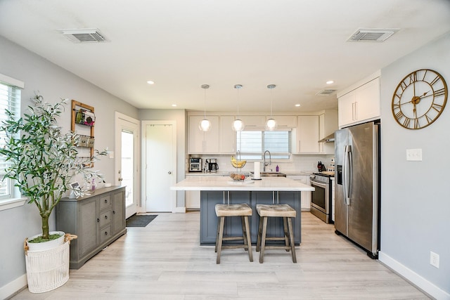 kitchen with sink, hanging light fixtures, stainless steel appliances, decorative backsplash, and white cabinets