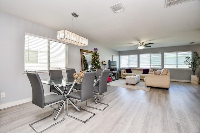 dining room featuring ceiling fan with notable chandelier and light wood-type flooring