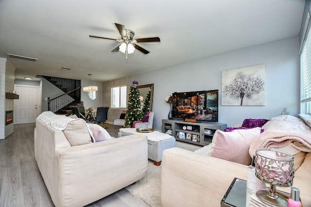 living room with ceiling fan with notable chandelier and light hardwood / wood-style floors