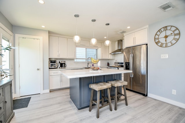 kitchen with white cabinetry, wall chimney exhaust hood, pendant lighting, decorative backsplash, and appliances with stainless steel finishes