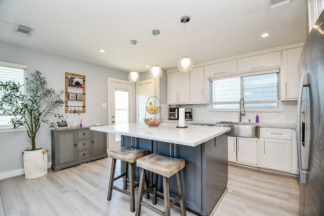 kitchen featuring decorative light fixtures, a center island, white cabinetry, and sink