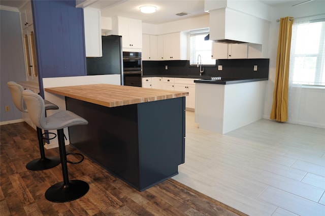 kitchen featuring white cabinetry, a kitchen breakfast bar, tasteful backsplash, refrigerator, and a kitchen island