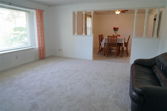 living room featuring light carpet, ornamental molding, ceiling fan, and a healthy amount of sunlight