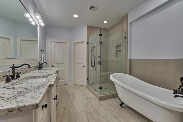 bathroom featuring vanity, a textured ceiling, and plus walk in shower