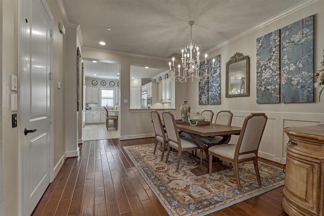 dining area featuring a textured ceiling, an inviting chandelier, dark wood-type flooring, and crown molding