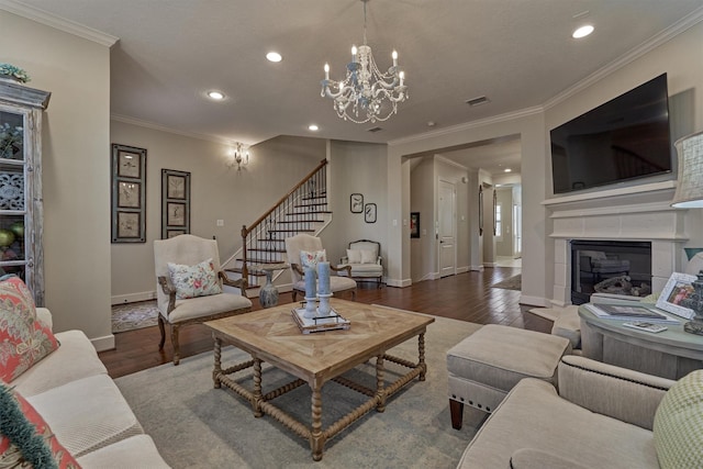 living room featuring wood-type flooring, a notable chandelier, ornamental molding, and a tiled fireplace