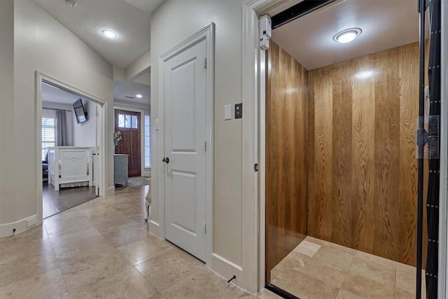 hall with elevator and wood walls