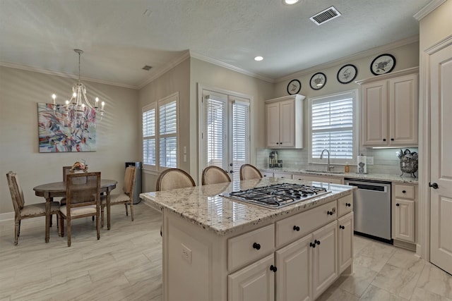 kitchen featuring a center island, backsplash, hanging light fixtures, sink, and appliances with stainless steel finishes