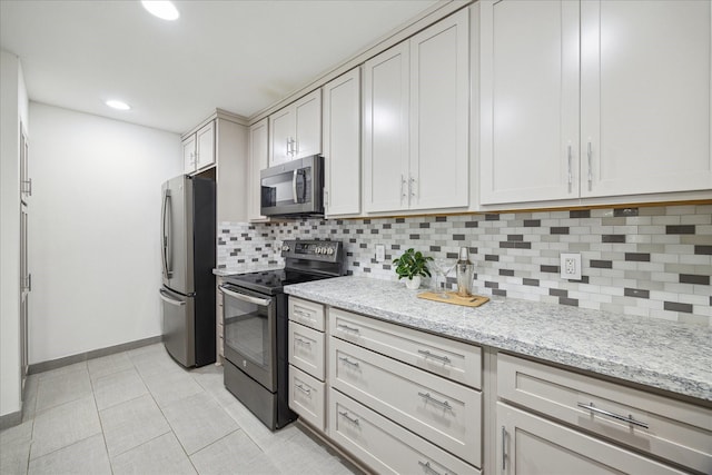 kitchen featuring backsplash, light stone countertops, light tile patterned floors, and appliances with stainless steel finishes