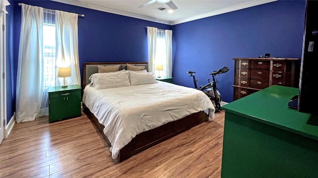 bedroom with multiple windows, hardwood / wood-style floors, ceiling fan, and crown molding